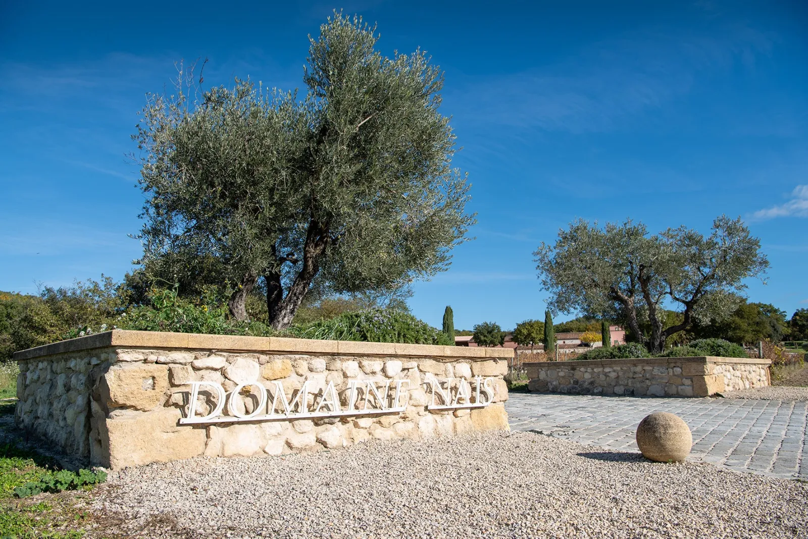 Entrée en pierre du Domaine Naïs bordée d oliviers à Rognes